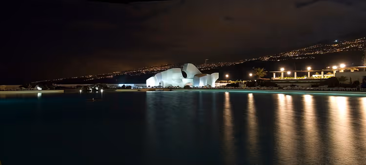 Gece ışıklandırılmış beyaz heykelle Lago Martiánez