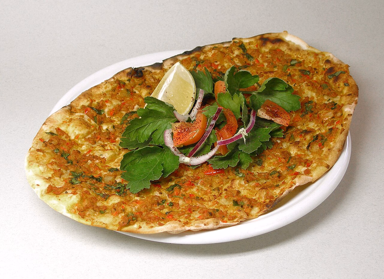 Lahmacun mit Kräutern, Tomaten und Zitrone auf einem Teller