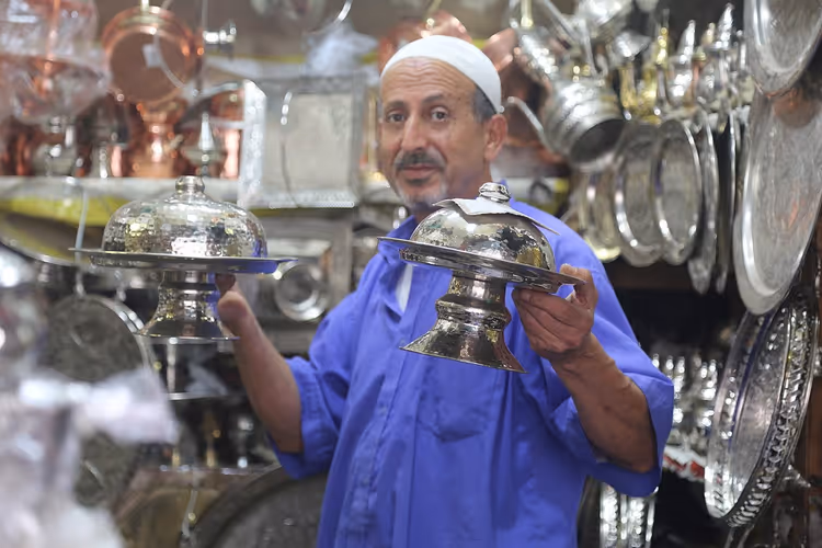 بائع يحمل صواني فضية في سوق أدوات الطهي