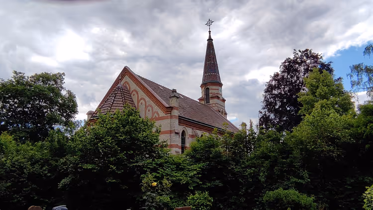 Église avec un haut clocher parmi les arbres verdoyants