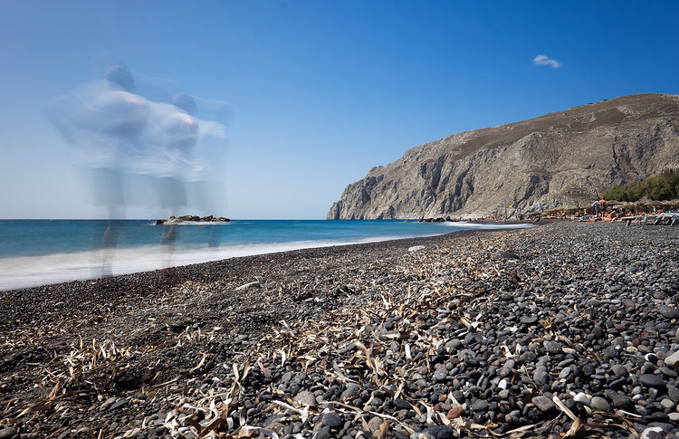 Der schwarze Kieselstrand von Kamari unterhalb des Felsens Mesa Vouno