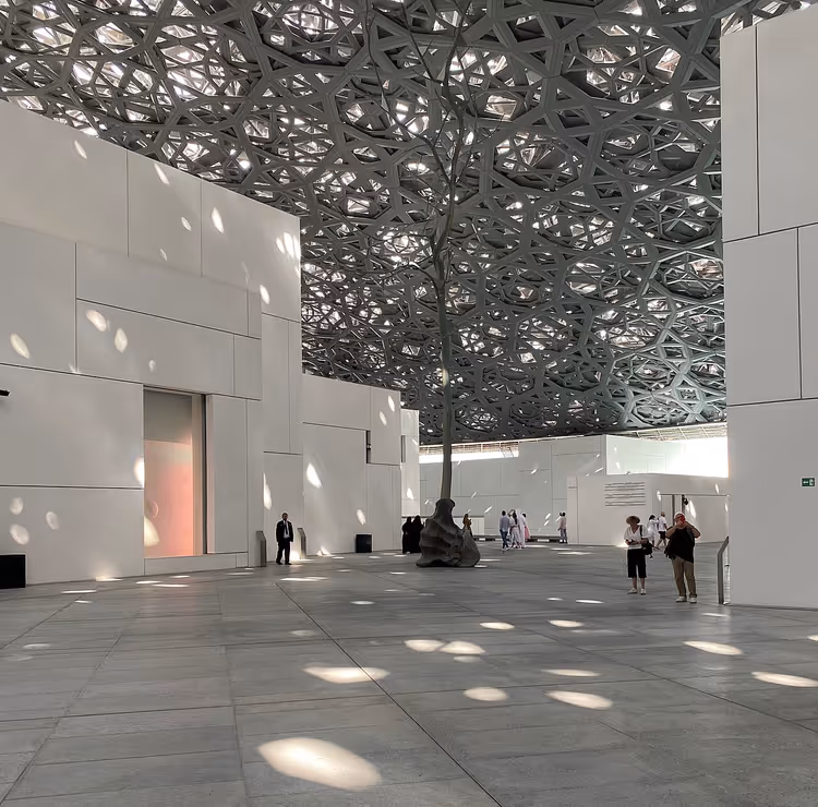 Louvre Abu Dhabi gårdsplass under gitterkuppelen med et tre