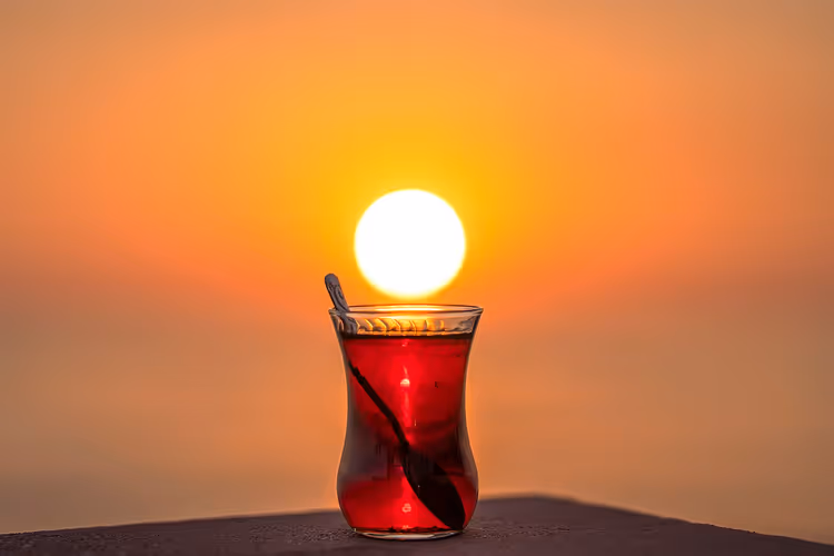 الشاي التركي الأسود في كوب زجاجي عند غروب الشمس