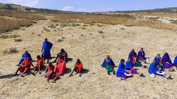 Kuru otların üzerinde oturan bir grup Maasai