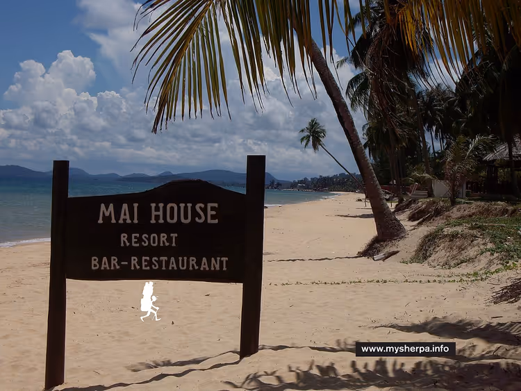 Bord van Mai House Resort op een tropisch strand met palmbomen