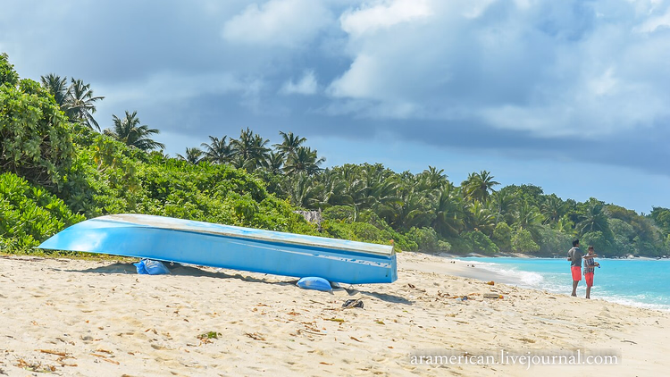 Boat on the sandy beach of Thoddoo among palm trees