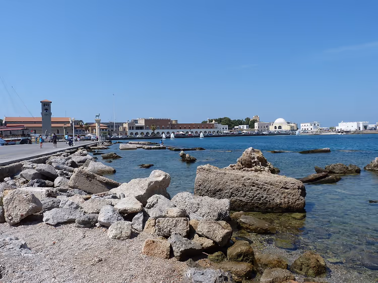 Rotsachtige kust en promenade van de haven van Mandraki