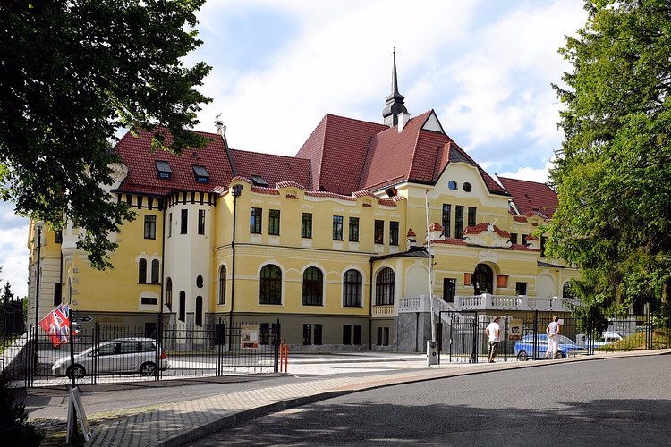 Gult slott-hotell med røde tak ved veien