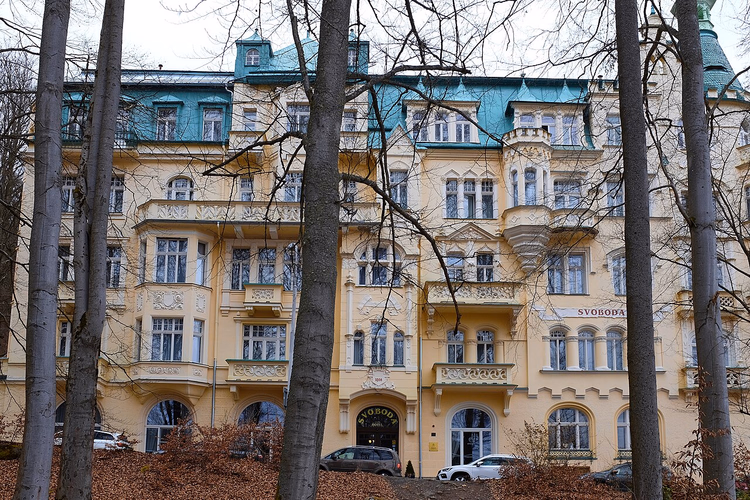 Fasade på Hotel Svoboda bak trestammer