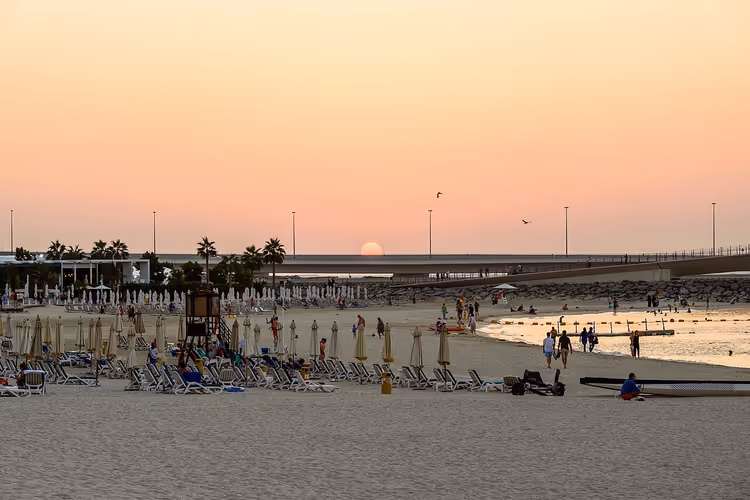Strand med solsenger og parasoller ved solnedgang i Dubai