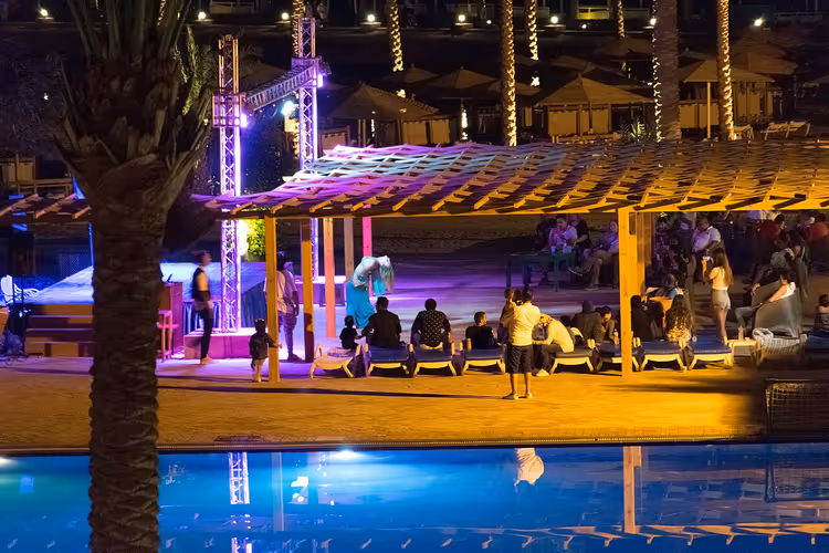 Otel yanında tente altında misafirlerle gece havuzu