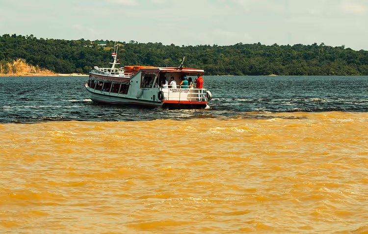 Barco en el punto de encuentro de las aguas oscuras y amarillas