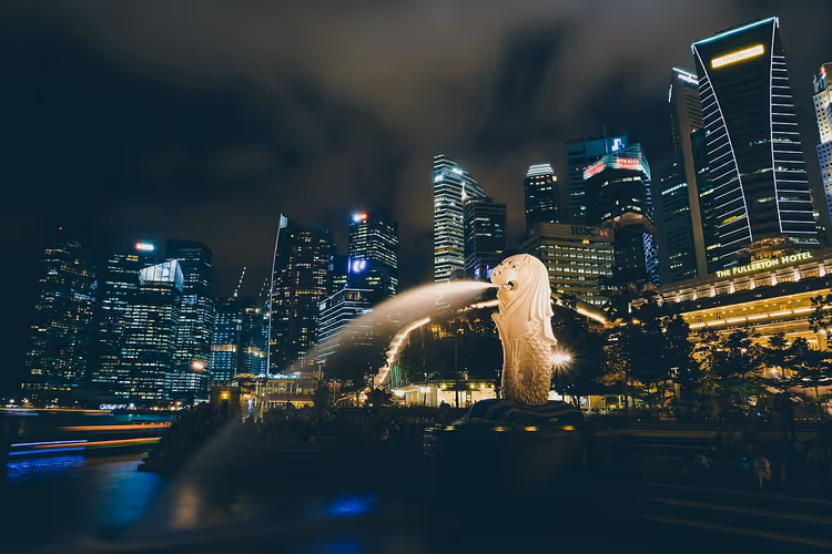 Merlion-standbeeld 's nachts tegen de skyline van Singapore