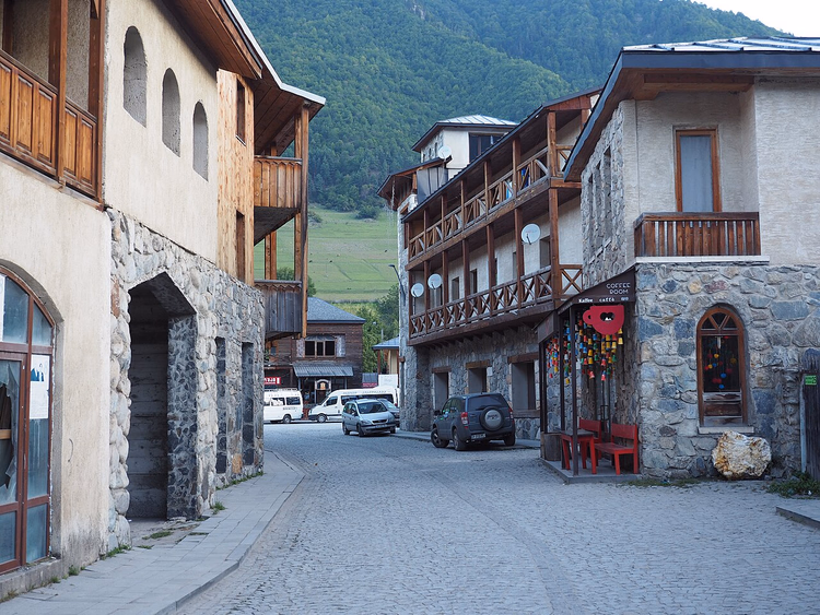 Kopfsteinpflasterstraße in Mestia mit Holzbalkonen