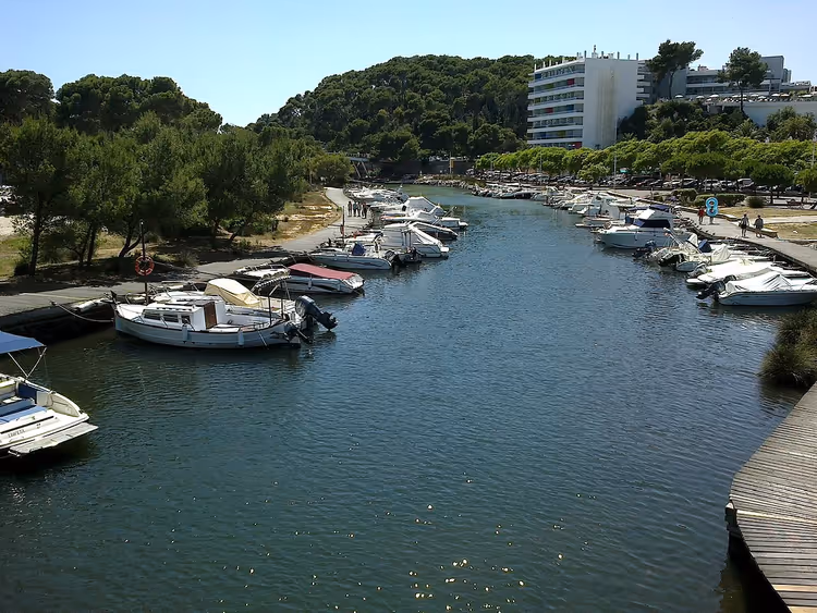 Boten in het kanaal van Cala Galdana met een hotel op de achtergrond