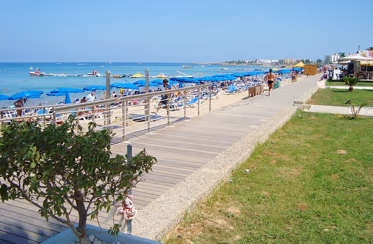 Holzpromenade entlang des Strandes mit Sonnenschirmen in Protaras