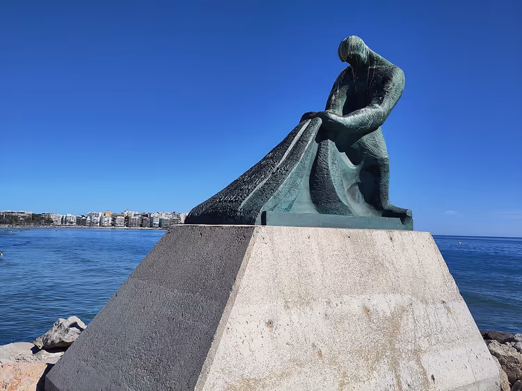 Бронзовий пам'ятник рибалці з сіткою біля моря