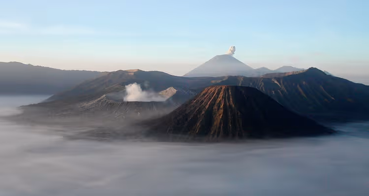Bromo bei Sonnenaufgang mit rauchendem Krater und Semeru