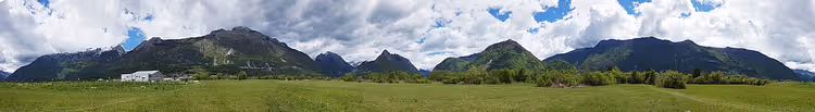 Bovec'te dağlar ve yeşil bir tarlanın panoraması