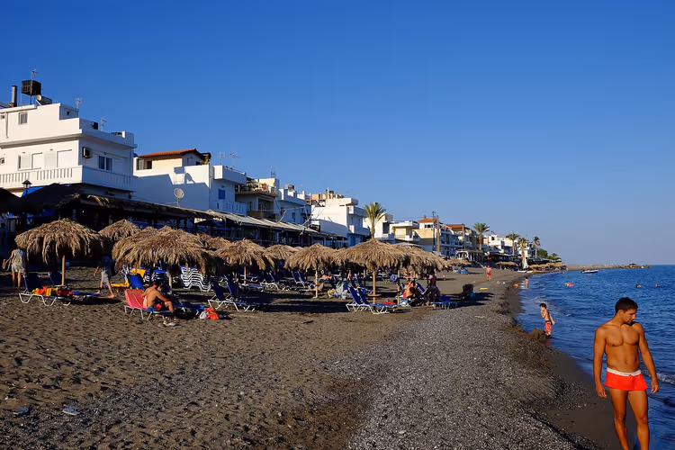 Strand von Myrtos mit Strohschirmen und Häusern