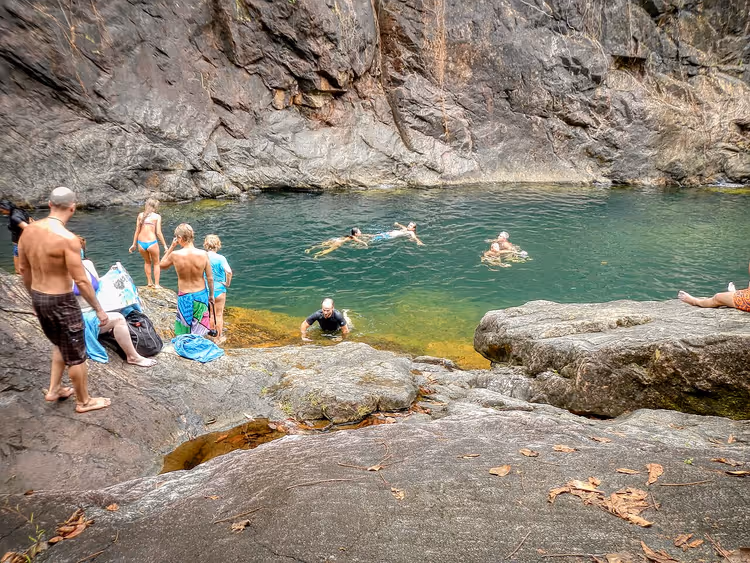 Folk som bader i et naturlig basseng blant klipper