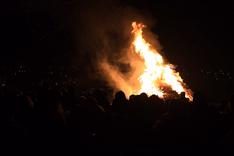 Menschenmenge um ein großes Silvesterfeuer bei Nacht
