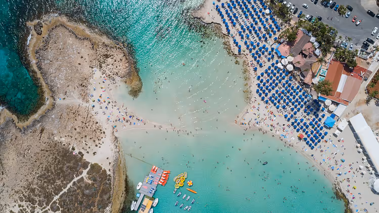 Luftaufnahme vom Nissi Beach mit Sonnenschirmen und Booten