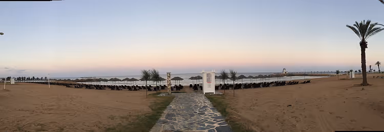 بانوراما الشاطئ مع كراسي استلقاء وممر يؤدي إلى البحر