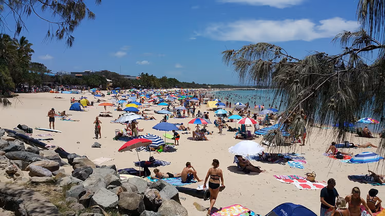 Folk og parasoller på en sandstrand