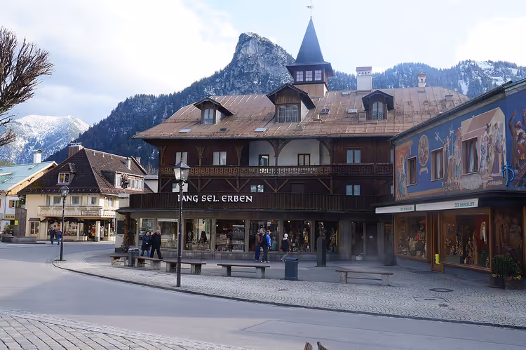 Beschilderde huizen in een straat in Oberammergau met bergen op de achtergrond