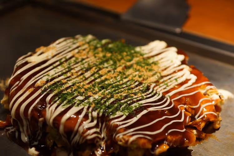 Okonomiyaki auf einer heißen Grillplatte mit Soße