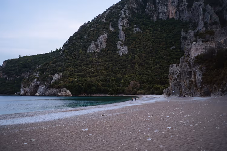 Yeşil dağlar ve deniz kenarında çakıl plajı