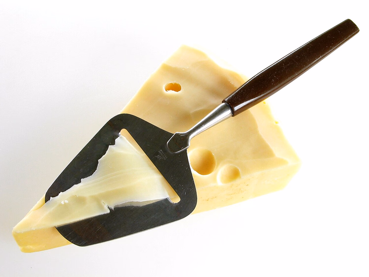 Kaasschaaf met houten handvat op een stuk kaas