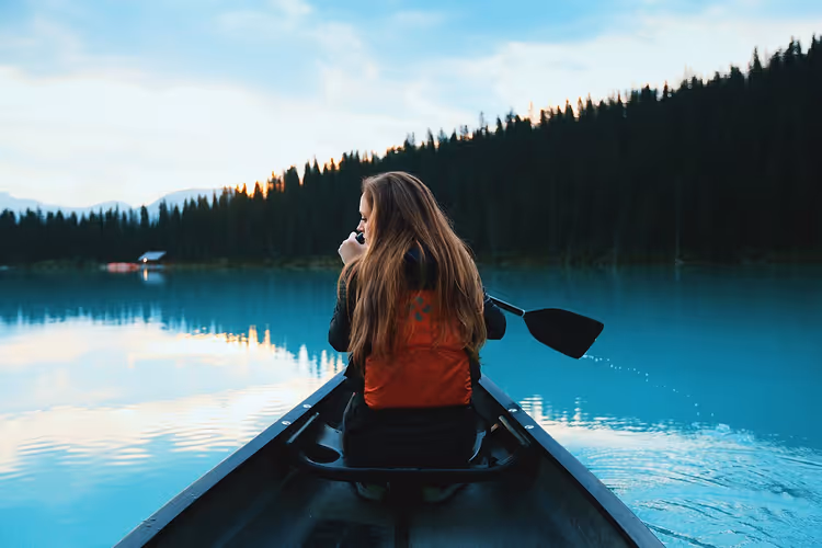 Kano op turquoise water tussen beboste bergen