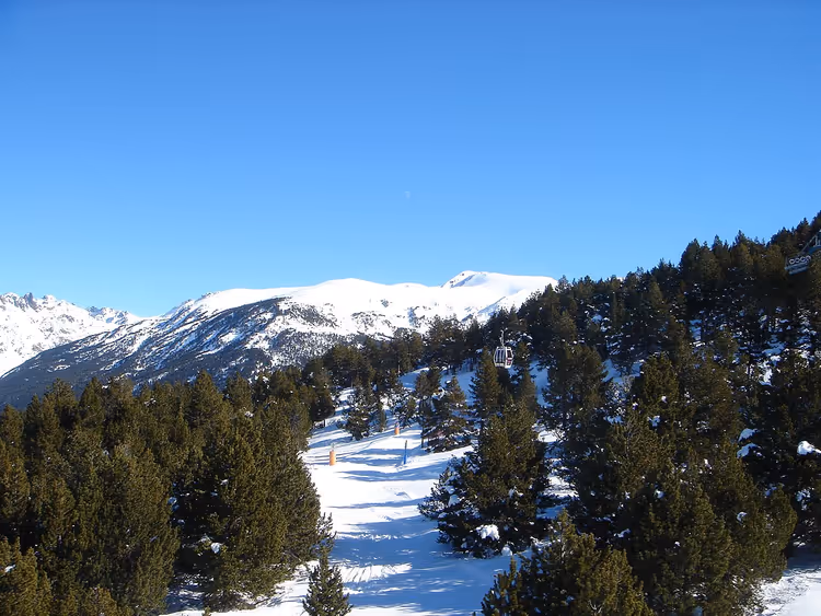 Montagne innevate in Andorra con pini e una pista da sci