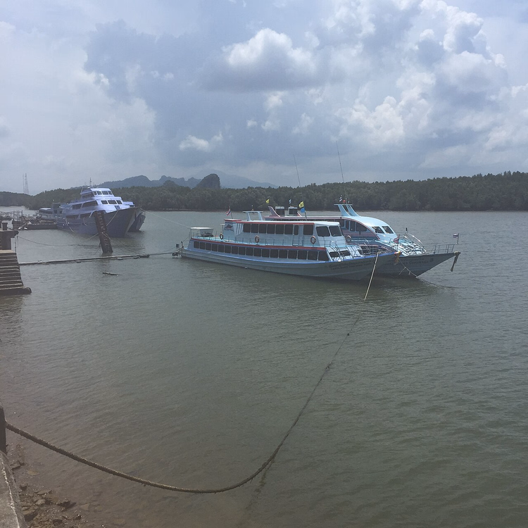 Boote am Pier von Krabi mit Karstfelsen im Hintergrund
