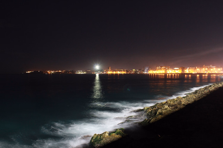 Malecon kıyısında denizin üzerinde gece Havana'sının ışıkları