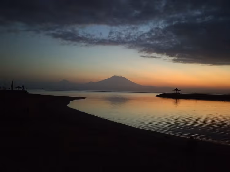 Soloppgang på Sanur-stranden med fjellsilhuett