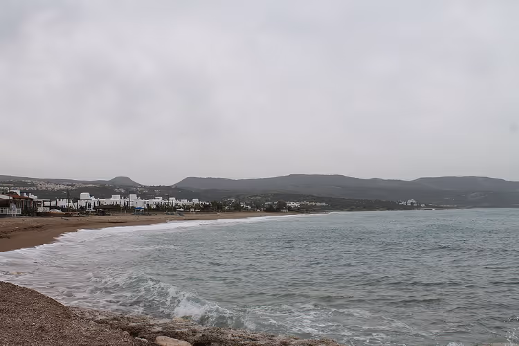 Latchi-stranden med bølger og bygninger ved kysten