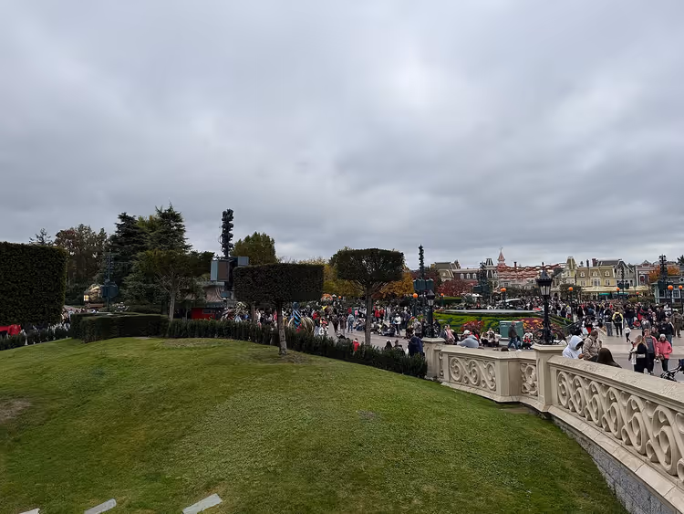 Kalabalık ziyaretçi ve çim alanıyla Disneyland Paris giriş bölümü
