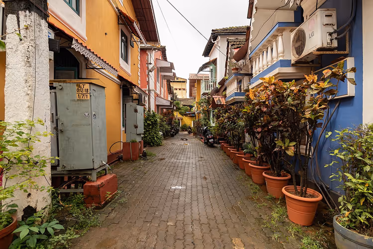 Schmale Gasse in Fontainhas mit bunten Häusern und Topfpflanzen