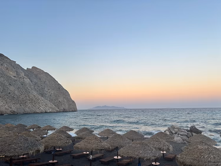 شاطئ بيريسا مع المظلات عند الغروب قرب صخرة ميسا فونو