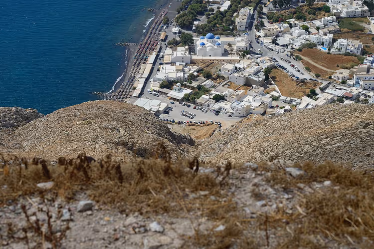 Der Strand von Perissa von oben, mit Liegen und dem weißen Ort