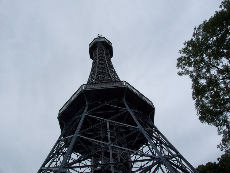 De Petřín-toren van onderaf tegen een bewolkte lucht