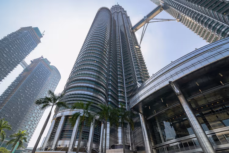 Petronas Towers von unten mit Palmen am Eingang
