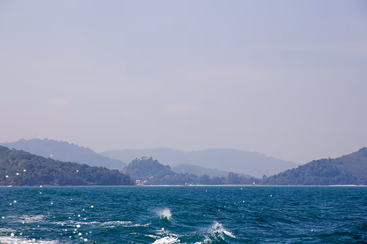 Wellen der Andamanensee und die bergige Küste von Phuket