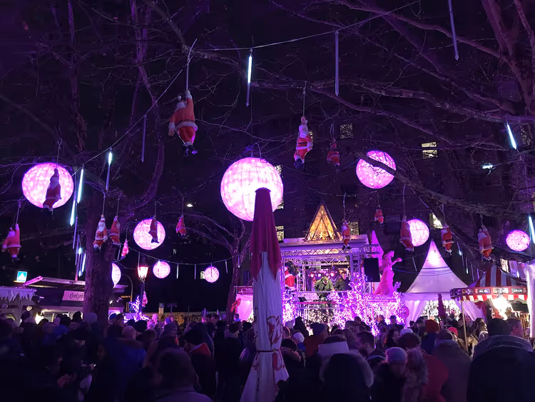 Bazar de Noël nocturne avec des lanternes roses et une foule