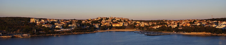 Panorama over bukta og landsbyen ved solnedgang