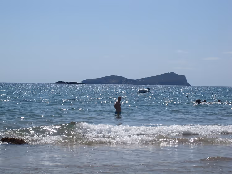 Deniz, dalgalar, suda bir kişi, uzakta bir ada