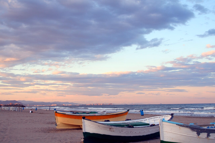 Fiskebåter på en strand i Valencia ved solnedgang